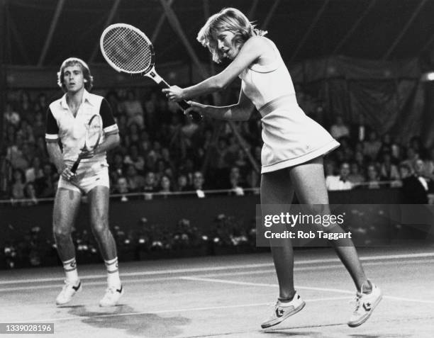 Chris Evert-Lloyd of the United States plays a double handed forehand return smash as her British partner John Lloyd looks on during the Love Doubles...