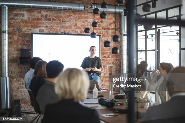 young businesswoman giving presentation to colleagues during meeting at office - storytelling recomendation stock-fotos und bilder