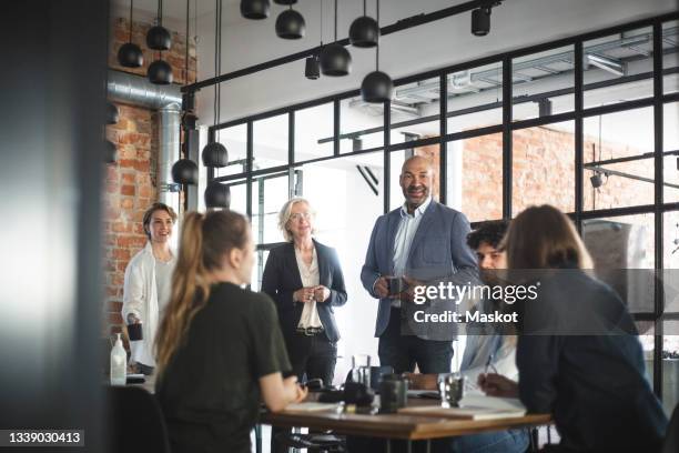 smiling male and female investors discussing with hackers during meeting in office - verwaltungsrat stock-fotos und bilder