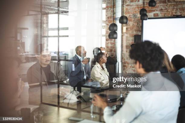 male and female professionals discussing over presentation at office - governing board foto e immagini stock