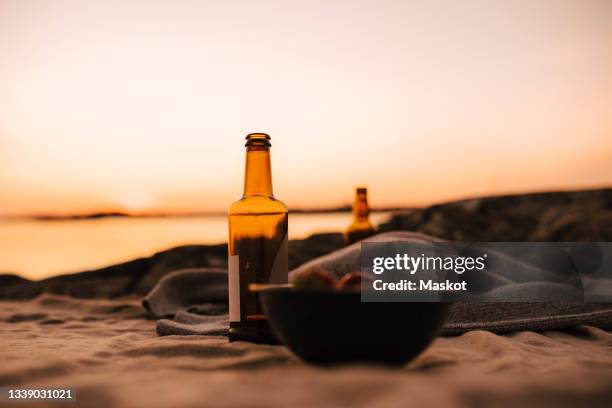 food bowl and beer bottle at lakeshore during sunset - beach bowl stock pictures, royalty-free photos & images