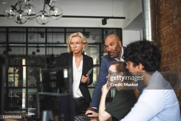 male and female advisors discussing over computer with hackers at startup company - storytelling recomendation stock-fotos und bilder