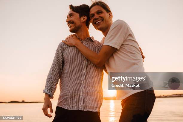 portrait of smiling man standing by boyfriend against lake - gay man bildbanksfoton och bilder