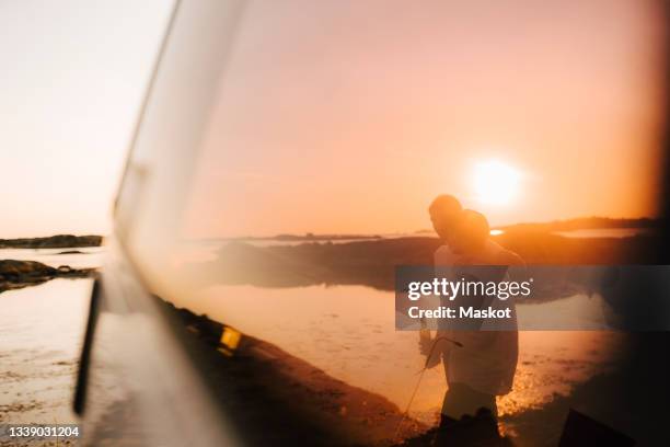 gay couple spending leisure time at lakeshore during sunset - göteborg silhouette bildbanksfoton och bilder
