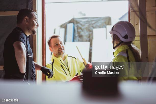 male and female construction workers discussing together at construction site - stockholm building stock pictures, royalty-free photos & images