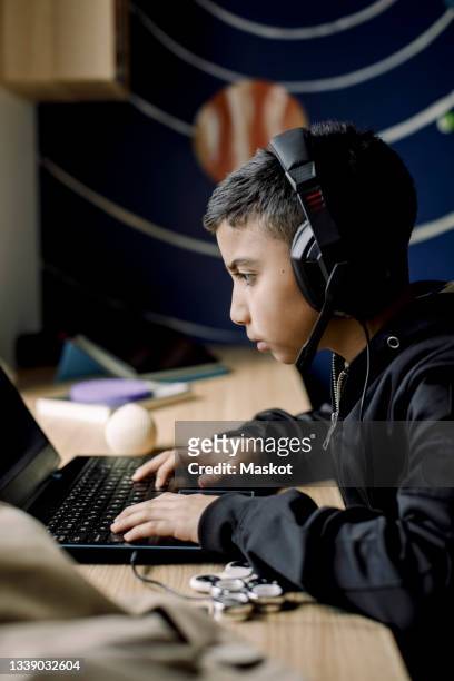 pre-adolescent boy playing game on laptop in bedroom - pre adolescent child bildbanksfoton och bilder