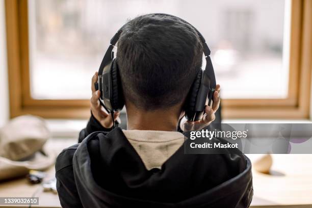 rear view of autistic boy with headphones at home - kid headphones stock pictures, royalty-free photos & images