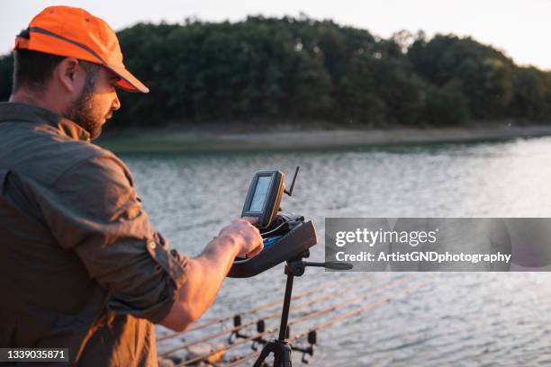 modern carp fishing, man is controlling sonar on electric boat. - sonhar stock pictures, royalty-free photos & images