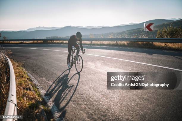 male cyclist driving up mountain road. - wielrennen stockfoto's en -beelden