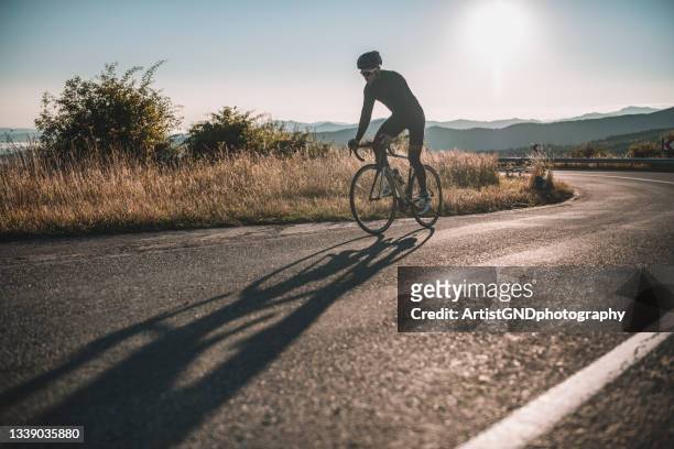 male cyclist driving up mountain road. - road cycling stock pictures, royalty-free photos & images