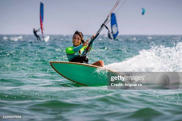 smiling woman kitesurfing in ocean with other kitesurfer, tarifa beach, cadiz, andalusia, spain - kite surfing stock pictures, royalty-free photos & images