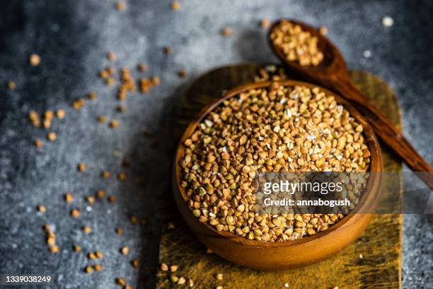 bowl of organic green buckwheat on a wooden chopping board - buckwheat stock pictures, royalty-free photos & images