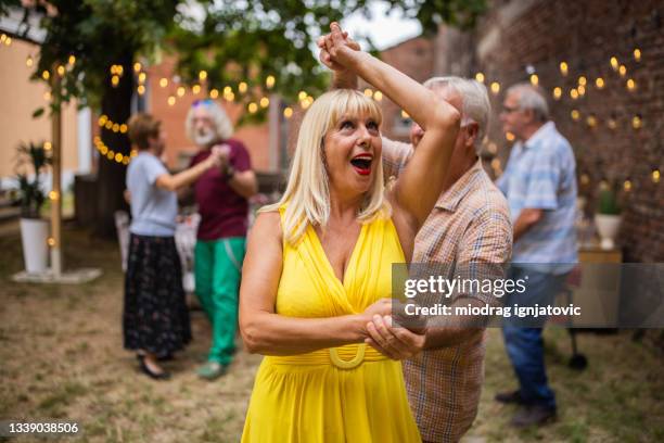 senior couples spending fun time together dancing on party in backyard on summer day - dansen stockfoto's en -beelden