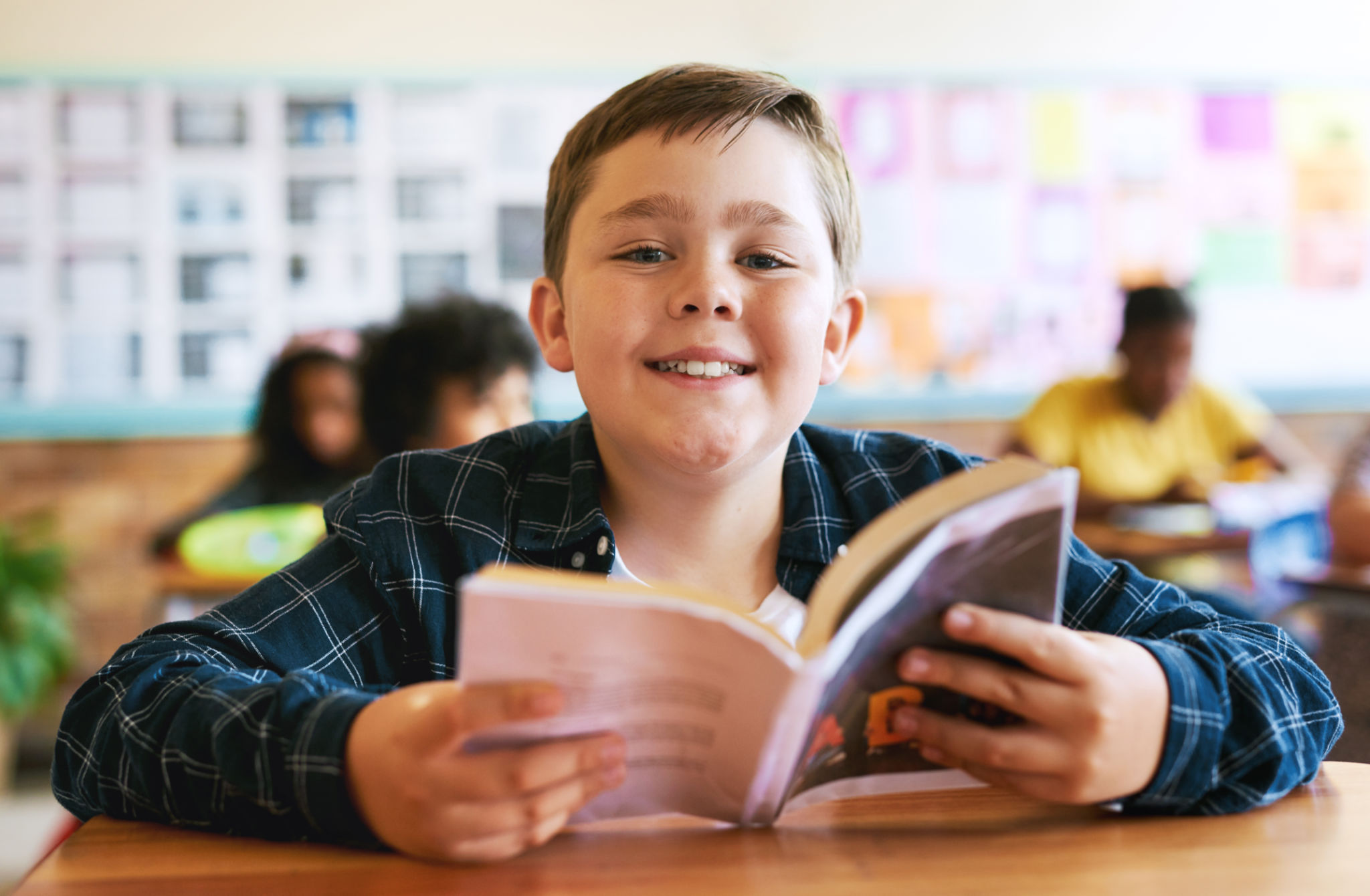 Shot of a young boy sitting in his classroom at school and reading a book Shot of a young boy sitting in his classroom at school and reading a book