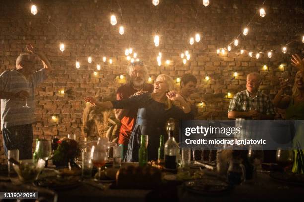 senior friends dancing and having fun at backyard while it's raining at night - senior man dancing on table stock pictures, royalty-free photos & images