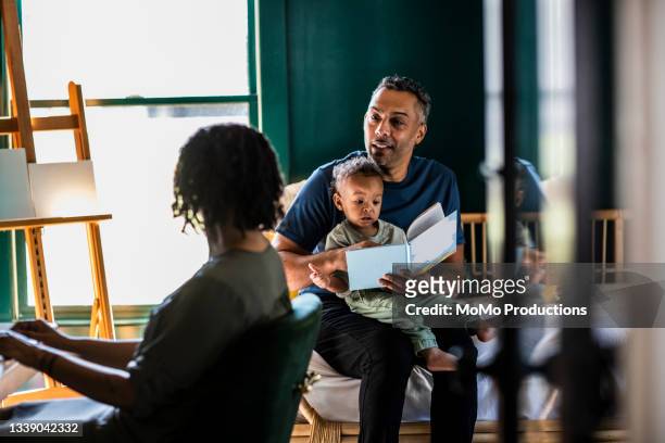 father reading a book to his toddler at home - nosotroscollection stockfoto's en -beelden
