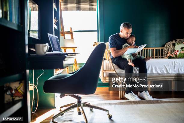 Father reading a book to his toddler at home