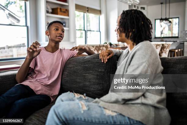 mother and son having conversation on sofa at home - mother son stock pictures, royalty-free photos & images