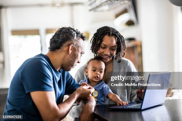 young family using laptop at home - family laptop stock pictures, royalty-free photos & images