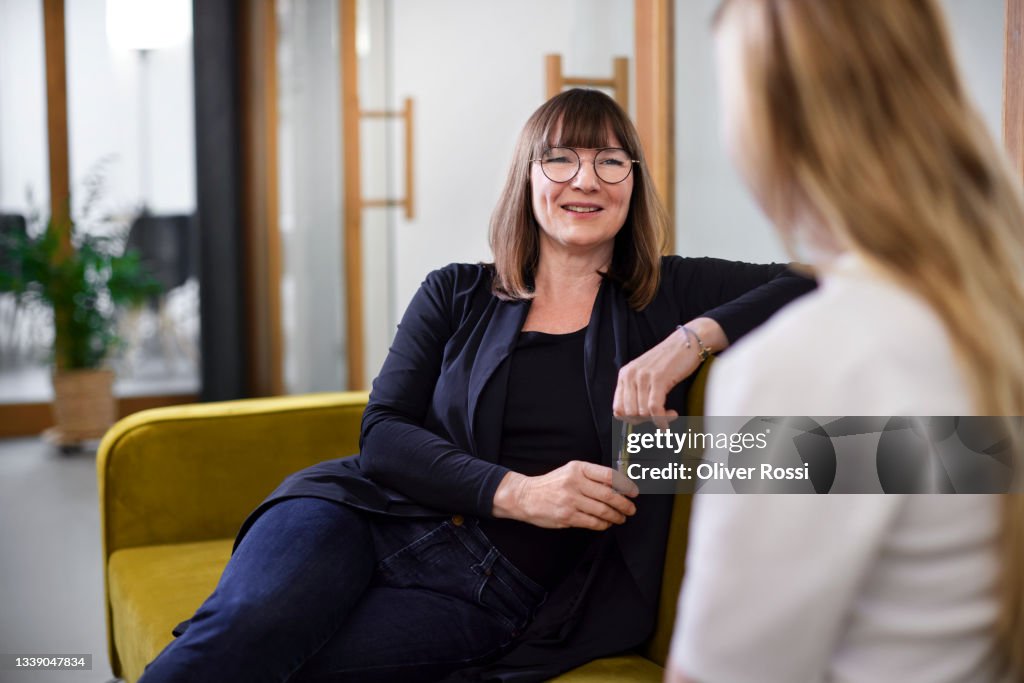 Two businesswomen talking on couch in office