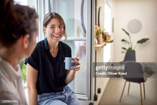 two businesswomen having a coffee break at the window in office - faire-une-pause photos et images de collection