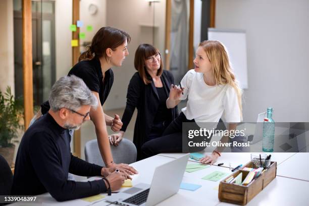 business team having a meeting in office - 50s woman writing at table imagens e fotografias de stock