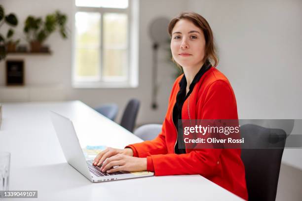 young businesswoman using laptop at desk in office - rood jak stockfoto's en -beelden