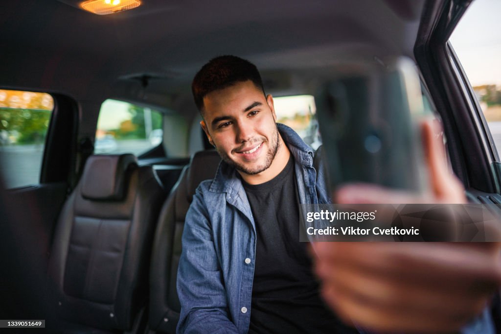 Happy man taking selfie on mobile phone in car