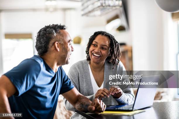 husband and wife using laptop at home - woman look straight black shirt stock pictures, royalty-free photos & images