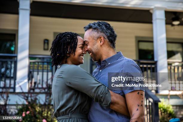 husband and wife embracing in front of new home - amor proprio photos et images de collection