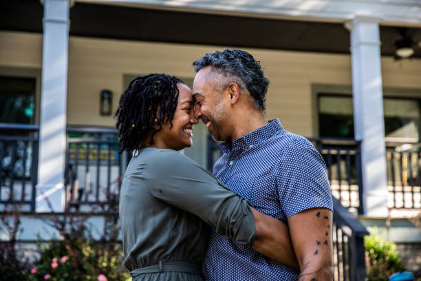 husband and wife embracing in front of new home - black man married to many wives stock pictures, royalty-free photos & images