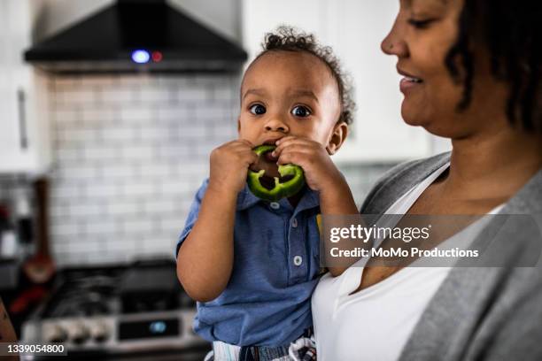 toddler eating a green pepper - groene paprika stockfoto's en -beelden