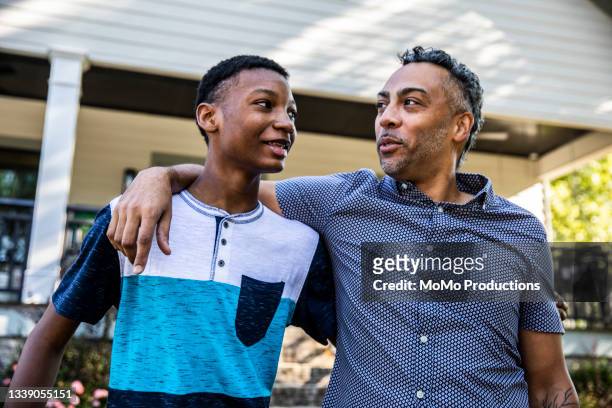 father and son talking in front of house - neue männlichkeit stock-fotos und bilder