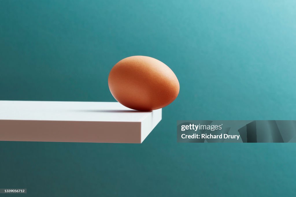 An egg teetering on the edge of a plank