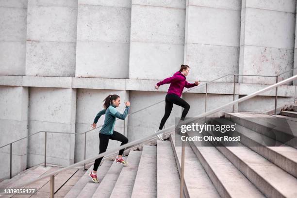 two young women running up stairs in the city - laufen sport stock-fotos und bilder