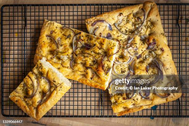 littlebourne, kent, england, uk. 13 august 2020. fresh foccacia bread cooling on a wire rack with a rosemary and red onion topping. - fougasse photos et images de collection