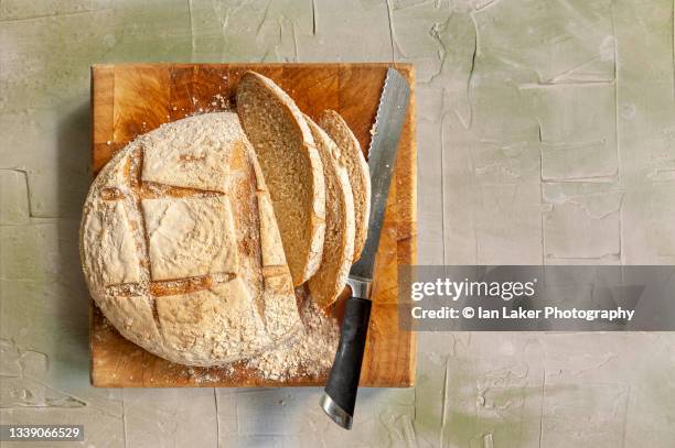 littlebourne, kent, england, uk. 3 september 2021. fresh bread sliced on a chopping board. - bread knife stock-fotos und bilder