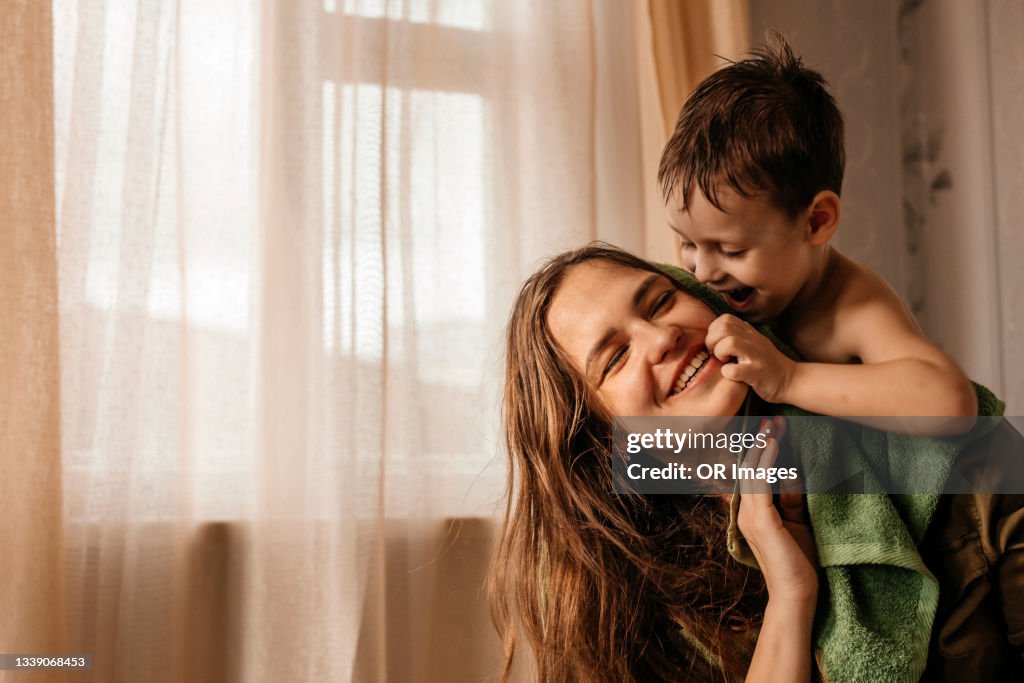 Happy mother with playful little son at home