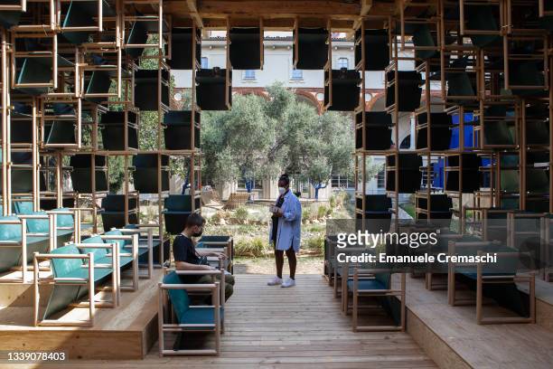 Two people visit School of Hope, a pavilion by Danish company Lendager built of more than 500 chairs made of industrial waste plastic and temporarily...