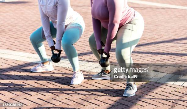 african-american women in city exercising, kettlebells - hurken stockfoto's en -beelden