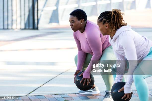 two african-american woman exercising with medicine ball - yoga ball outside stock pictures, royalty-free photos & images