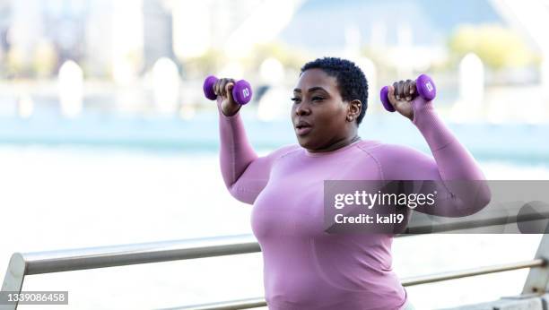 屋外で手の重みを持ち上げるアフリカ系アメリカ人の女性 - ウエイトトレーニング　女性 ストックフォトと画像