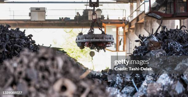 transporting scrap steel by crane, recycling of material - magneet stockfoto's en -beelden