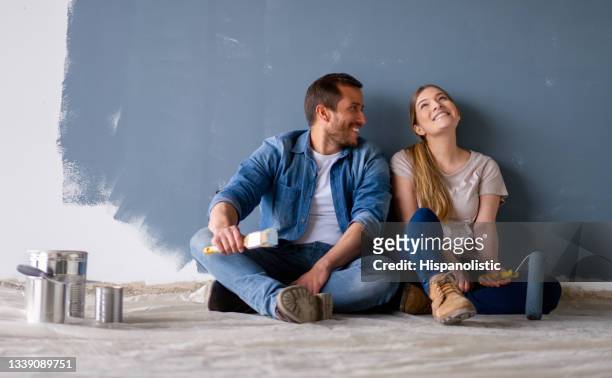 loving couple having fun renovating their house and painting the walls - home interior stock pictures, royalty-free photos & images