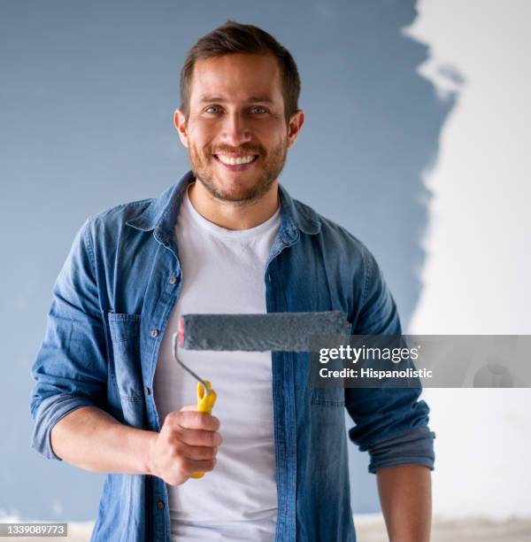 happy man having fun painting his house - holding paint roller stock pictures, royalty-free photos & images