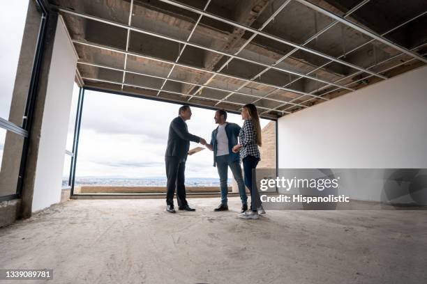 カップルに建設中の家を示し、握手でそれらを挨拶不動産業者 - 不動産開発業者 ストックフォトと画像
