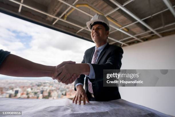 architect greeting client with handshake at a construction site - real estate developer stock pictures, royalty-free photos & images