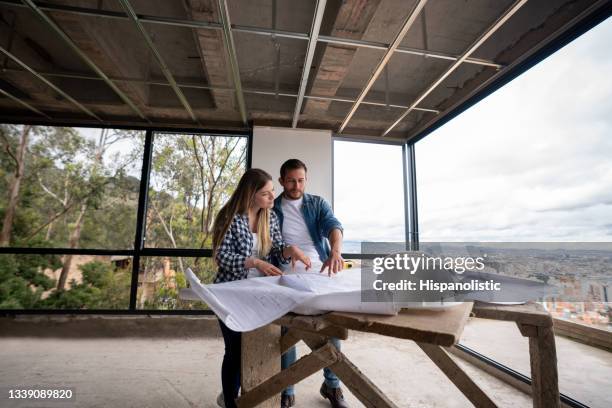 couple building their own house and looking at the blueprints at a construction site - building contractor bildbanksfoton och bilder