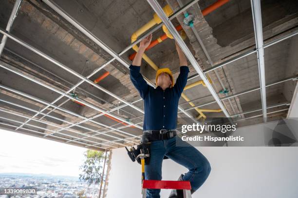 bauunternehmer überprüft die rohre auf einer baustelle - hispanic construction worker stock-fotos und bilder