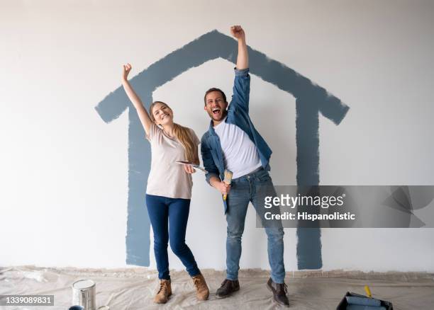 excited couple looking very happy painting their house - couple celebrating stock pictures, royalty-free photos & images